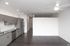 Modern apartment kitchen with sleek gray cabinets, stainless steel appliances, and a spacious open layout with hardwood floors.