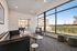 Bright and modern living area with large windows, featuring a stylish leather sofa, contemporary armchair, and chic decor, perfect for relaxation and entertainment.