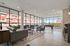 Modern, sunlit apartment lounge with floor-to-ceiling windows, cozy seating, and a pool table, perfect for relaxation and entertaining.