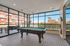 Contemporary game room with a sleek pool table, expansive windows, and vibrant urban views perfect for relaxation and entertainment.