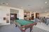 Elegant community lounge featuring a chic pool table, modern bar area, and cozy seating with contemporary decor.