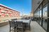 Expansive balcony view with stylish outdoor seating and modern architecture under a clear blue sky.