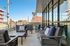 Elegant urban balcony with chic outdoor seating, offering city skyline views and abundant sunlight.