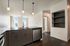 Modern kitchen with sleek dark cabinets, pendant lighting, and expansive windows offering bright natural light.