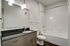 Modern bathroom with sleek vanity, large mirror, and bathtub featuring clean, contemporary design.