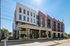 Modern apartment building with sleek, contemporary design featuring large windows and a vibrant urban setting.