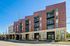 Contemporary urban apartment complex with stylish brick facade, featuring private balconies and large windows, located on a bustling street.