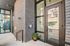 Chic modern apartment entrance with sleek brick facade, large glass panels, and a welcoming touch of greenery in a stylish pot.