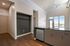 Modern apartment interior with sleek kitchen island, high ceilings, and bright natural light from large windows opening to a balcony.