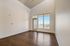 Bright, open living space with high ceilings and large windows overlooking a serene balcony view.