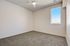 Bright and spacious room featuring soft carpet flooring, a modern ceiling fan, and a large window with serene outdoor views.