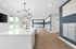 Bright and modern mailroom featuring sleek white counters, stylish chandelier, and ample natural light.