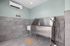 Modern pet washing station with stainless steel tub and stylish gray tile walls, featuring elegant bone-shaped floor mat and efficient wall-mounted faucet.
