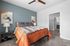 Elegant bedroom with cozy orange accents, plush bedding, and modern decor, adjacent to a stylish bathroom.