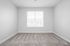 Bright, cozy room with fresh carpeting and a large window for natural light.