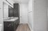 Elegant bathroom with sleek dark cabinetry, granite countertop, and modern fixtures beside a spacious walk-in shower.