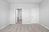 Modern apartment bedroom with plush carpeting, framed by elegant white doors leading to a cozy bathroom.