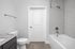 Elegant bathroom featuring a modern bathtub, sleek tiled walls, and granite countertop, offering a blend of style and functionality.
