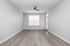 Bright, spacious room with modern gray flooring, large window, and ceiling fan, ideal for an airy and inviting living space.