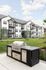 Modern apartment complex with a sleek outdoor grill station and beautifully landscaped grounds.