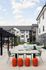 Vibrant apartment courtyard featuring modern outdoor seating, playful orange stools, and stylish hammocks under a clear sky.