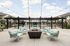 Chic outdoor lounge area with modern fire pit, plush seating, string lights, and stylish pergola overlooking a vibrant swimming pool.