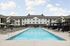 Elegant apartment complex featuring a sparkling outdoor pool, surrounded by modern lounge chairs and shaded seating areas.
