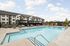 Inviting apartment complex with a sparkling outdoor pool, modern lounging areas, and vibrant landscaping, perfect for relaxation and entertainment.