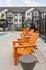 Contemporary apartment complex with vibrant orange chairs by a pristine pool, offering a perfect blend of relaxation and modern living.
