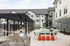 Modern apartment complex with outdoor entertainment area, featuring hammocks, a sleek barbecue grill, and stylish seating under a pergola.