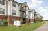 Modern apartment complex with brick and siding exteriors, featuring lush landscaping and a welcoming facade.