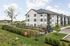 Modern apartment complex with pristine architecture, surrounded by lush greenery and open spaces, offering a serene living environment.