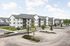 Modern apartment complex featuring spacious parking and landscaped greenery, surrounded by a serene environment.