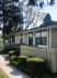 Charming single-story apartment with welcoming front yard, framed by lush greenery and fenced garden pathway.