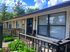 Charming apartment exterior with modern design, large windows, and vibrant greenery on a sunny day.