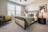 Charming bedroom with elegant decor, featuring a cozy bed, stylish armchair, and ample natural light through large windows.
