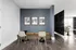 Elegant modern seating area with sleek chairs and round glass tables against a stylish navy accent wall, and artistic framed prints adding a sophisticated touch.
