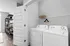 Modern laundry room with stylish white washing machine and dryer, accompanied by sleek shelving, in a chic apartment setting.