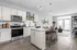 Modern open-concept kitchen with sleek stainless steel appliances, a chic dining area, and abundant natural light through double glass doors.