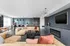 Luxurious open-concept living room with stylish d&eacute;cor, featuring modern furniture, a chic fireplace, and a sleek kitchen with designer pendant lights.