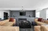 Luxurious modern living room featuring plush tan leather sofas, a sleek fireplace, and a stylish chandelier, perfect for cozy gatherings.