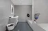 Modern, spacious bathroom with sleek grey tiles and minimalist design, featuring a stylish vanity, shower area, and artistic decor.