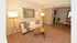 Inviting living room with plush carpeting, stylish sofa, and contemporary lighting, seamlessly connected to dining area with elegant wooden flooring.