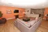 Modern entertainment room with cozy seating, stylish orange accent wall, and sleek kitchen area, perfect for hosting gatherings.
