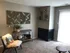 Cozy living space with stylish decor, featuring a modern fireplace, artful wood panel wall art, and a comfortable reading nook with plush seating.