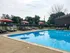 Inviting outdoor swimming pool with stylish lounge chairs and vibrant red umbrellas, perfect for relaxation and leisure.