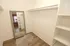Spacious walk-in closet with sleek white shelves, full-length mirror, and elegant wooden flooring.