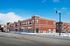 Charming brick apartment complex with large windows and modern design, set in a picturesque snowy neighborhood under a clear blue sky.
