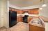 Modern kitchen with warm wooden cabinetry, sleek black appliances, and elegant pendant lighting.