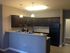 Contemporary kitchen featuring sleek dark cabinets, elegant granite countertops, and modern lighting, perfect for culinary enthusiasts.
